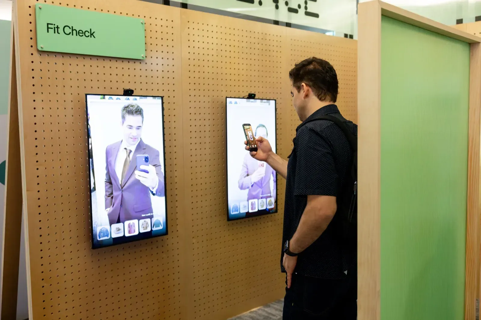 Επισκέπτης δοκιμάζει το Fit Check, μια AR try-on εμπειρία με εικονικό ρούχο σε δύο κάθετες οθόνες