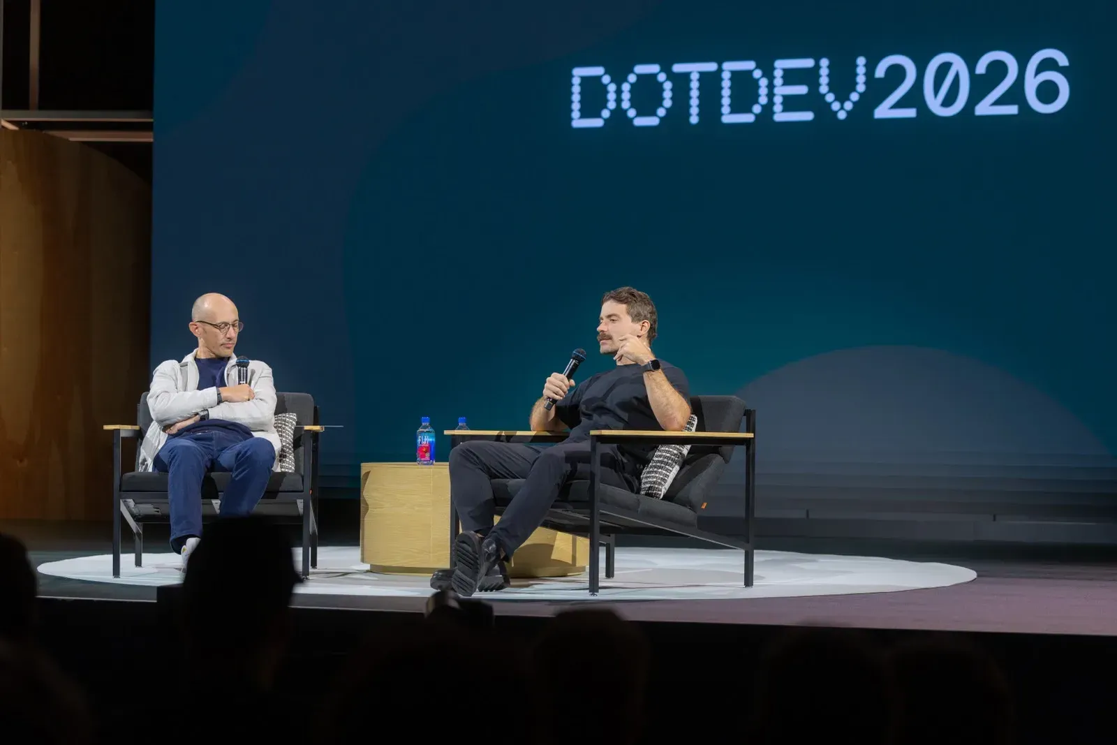 Δύο άνδρες σε πολυθρόνες κάνουν fireside chat στην κεντρική σκηνή του DotDev