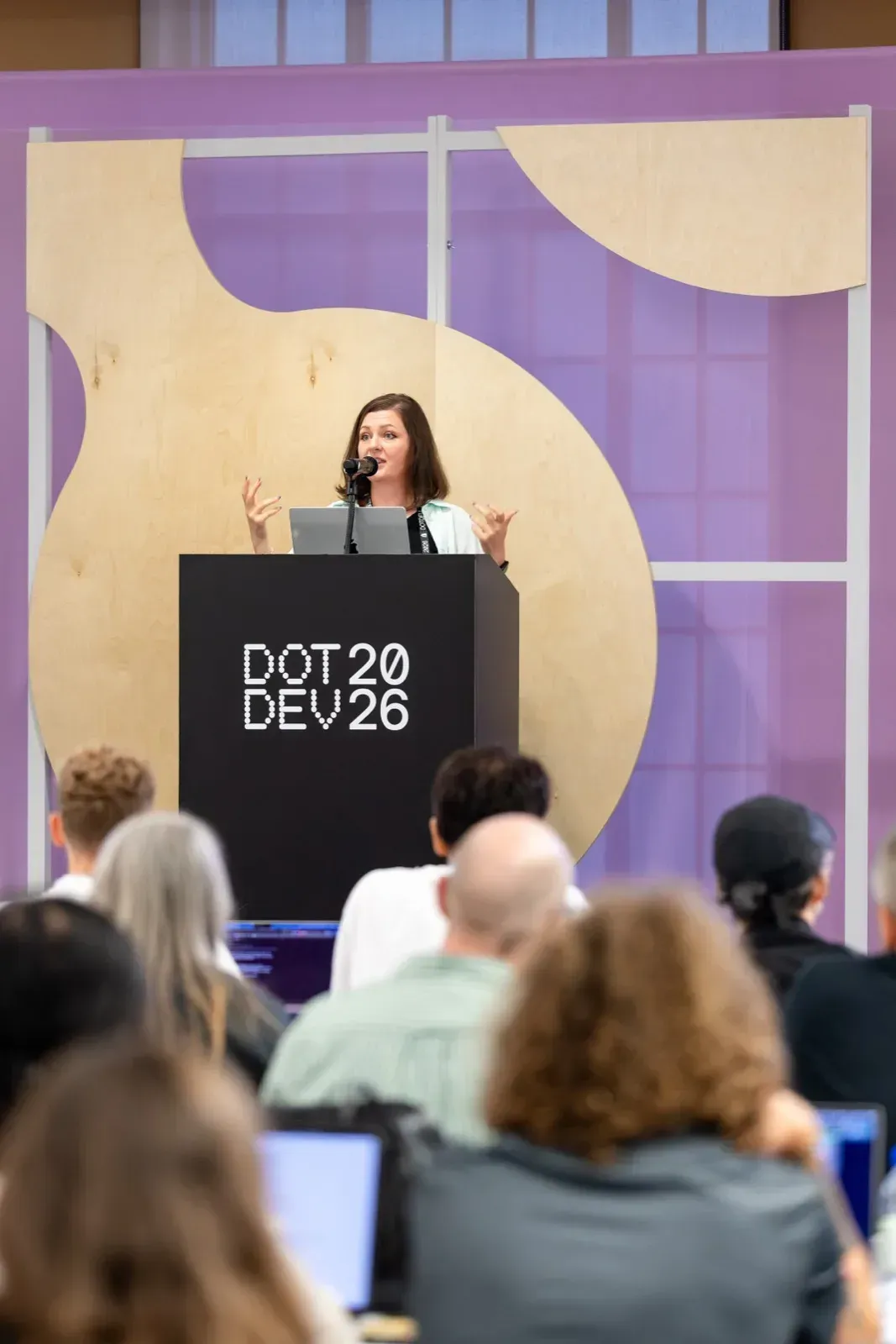 Ομιλήτρια παρουσιάζει σε podium DotDev 2026 σε κοινό breakout session