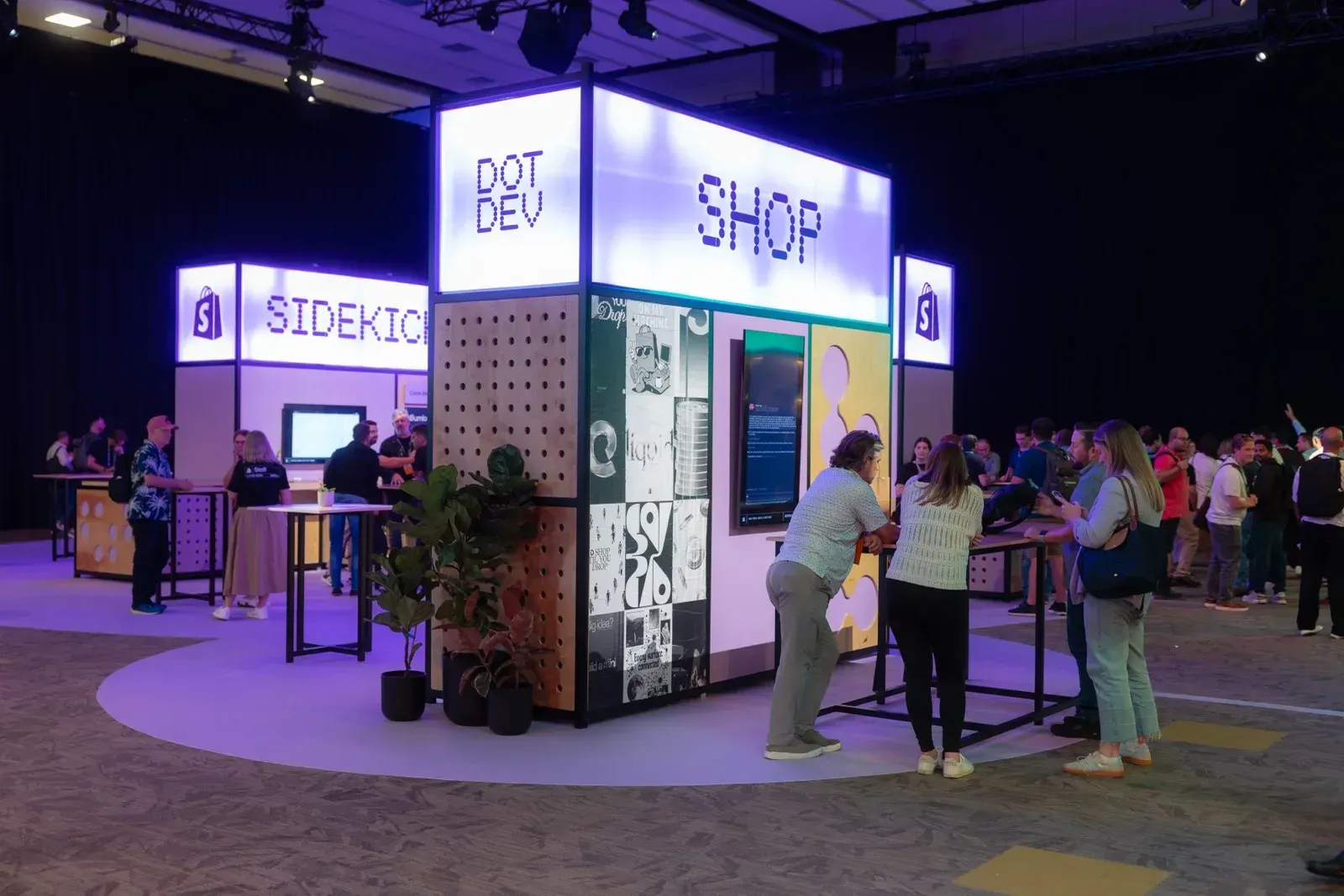 Φωτεινοί πύργοι booth με σήμανση Shop και Sidekick στο expo floor του DotDev