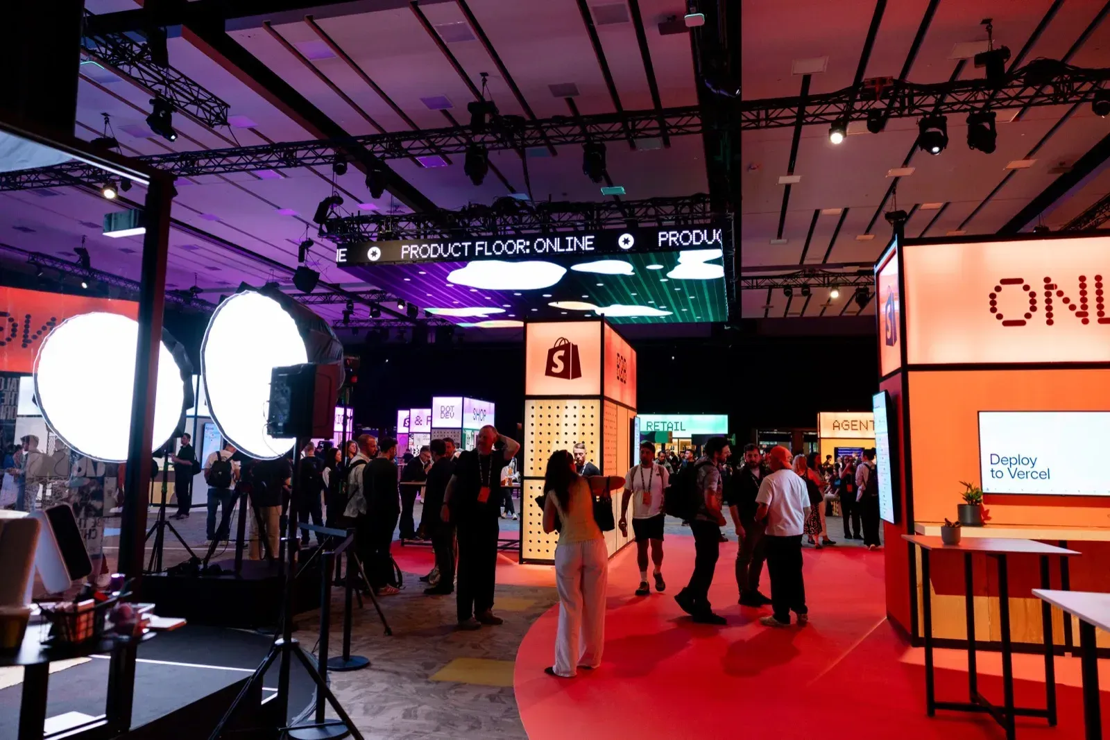 Ευρεία άποψη του Product Floor στο DotDev με booth και σήμανση Deploy to Vercel και Online/Retail/Agent