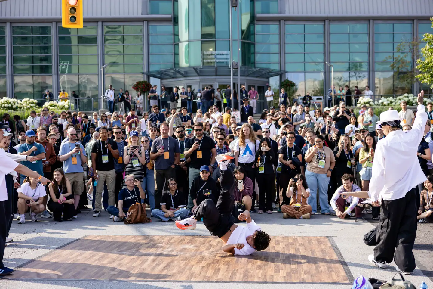 Breakdancer δίνει παράσταση σε ξύλινο πάτωμα μπροστά σε μεγάλο πλήθος έξω από το συνεδριακό κτίριο